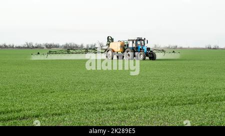 Trattore con dispositivo di spruzzatura per fertilizzante finemente disperso. Foto Stock