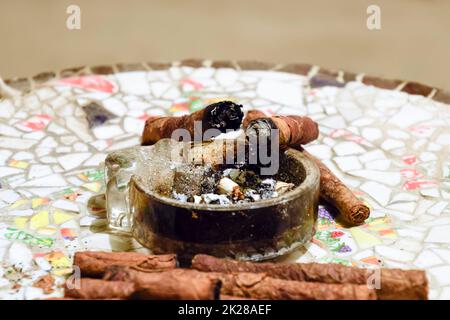 Sigari fatti in casa da frondoso foglie di tabacco su una tavola di ceramica. Posacenere e sigari. Foto Stock