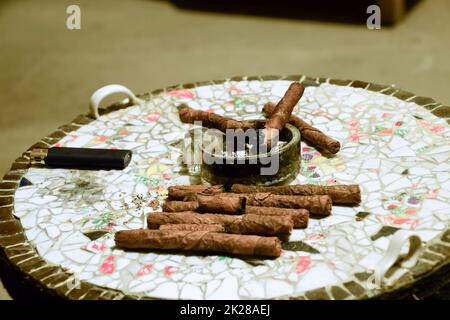 Sigaro e posacenere sul tavolo dei pezzi incollati di ceramica Foto Stock