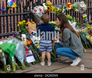 Londra, Regno Unito - Settembre 9th 2022: Una madre e un bambino guardano i fiori lasciati dai bravissimi wishers a Buckingham Palace a Londra, in memoria di Elizabeth II, wh Foto Stock