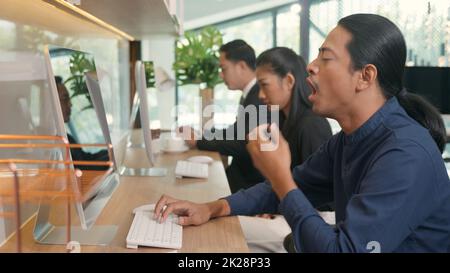 Gli uomini d'affari stanchi sbadigliano durante il lavoro sul computer seduto alla scrivania ufficio Foto Stock