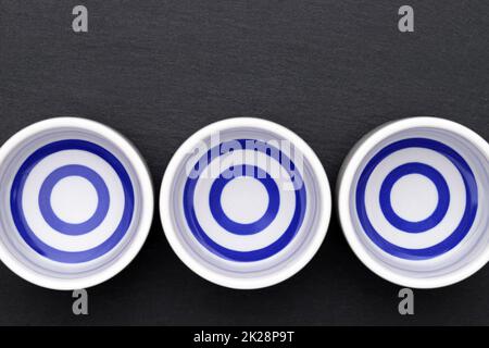 Sake giapponese in tradizionale tazza di ocoko in ceramica su sfondo nero Foto Stock