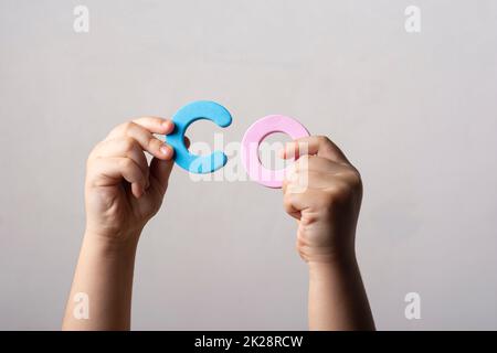 Le mani che tengono due lettere dell'alfabeto spugnoso in blocco nella parola CO Foto Stock