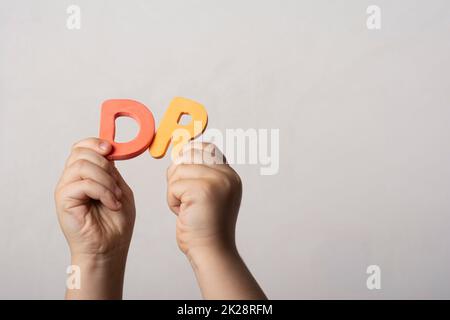 Le mani che tengono due lettere dell'alfabeto spugnoso in blocco nella parola DR Foto Stock
