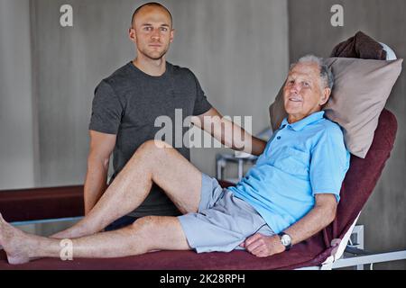 Physio ne prende due. Ritratto di un uomo anziano che ha una sessione di fisioterapia con un terapista maschile. Foto Stock