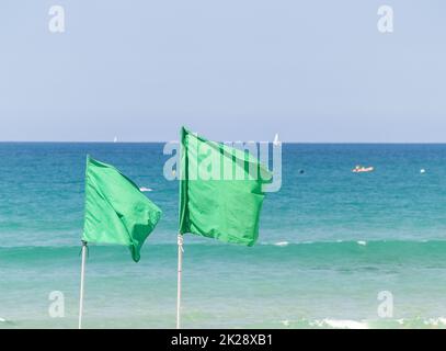 Due bandiere verdi sullo sfondo della costa sfocata. Foto Stock