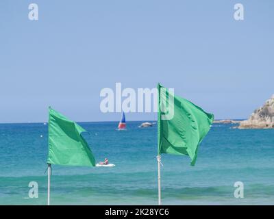 Due bandiere verdi sullo sfondo della costa sfocata. Foto Stock