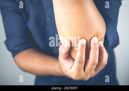 L'uomo è un gomito di dolore. Questi sintomi possono causare da sport, duro lavoro con il braccio. Primo piano. Foto Stock