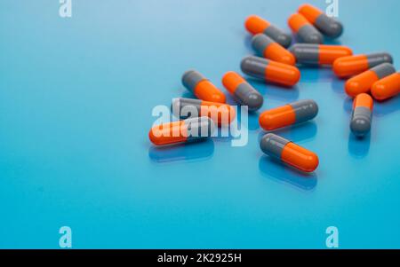 Capsule di antibiotico arancione-grigio su sfondo blu. Resistenza agli antibiotici. Industria farmaceutica. Farmaco da prescrizione. Produzione di capsule pills. Farmacologia e tossicologia. Foto Stock