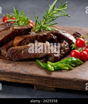 un pezzo di ribeye di manzo arrosto tagliato a pezzi su un tagliere marrone d'annata. Bravo Foto Stock