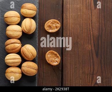 dadi da dessert al forno con latte condensato su tavola nera in ardesia, vista dall'alto Foto Stock