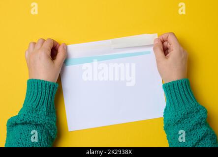 la mano femmina contiene buste di carta bianca su sfondo arancione, vista dall'alto. Invio e ricezione della corrispondenza Foto Stock