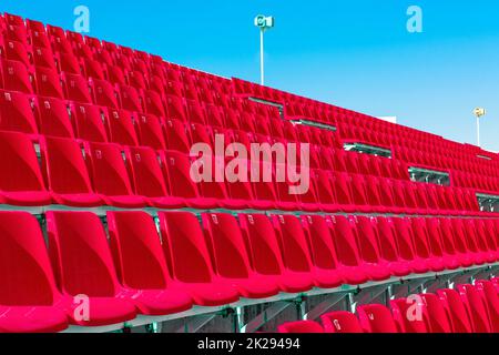 Fila di posti a sedere vuoti in plastica rossa sullo stadio sulla terrazza Foto Stock