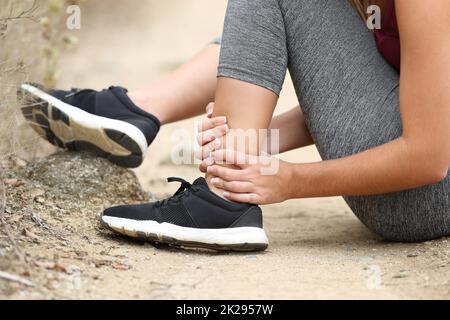 Runner afferrare la caviglia distesa in montagna Foto Stock