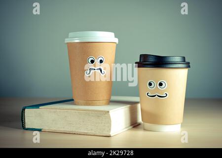 Due graziose tazze da asporto e un libro Foto Stock