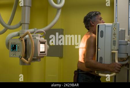 Esame medico radiografico di un uomo anziano in un ospedale moderno (immagine dai toni colorati) Foto Stock