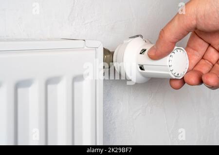 La mano ruota la manopola di riscaldamento della batteria Foto Stock