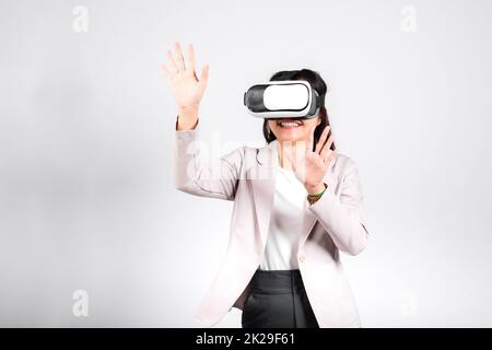 Donna sorridente fidata, indossa il visore VR che tocca l'aria durante l'esperienza di realtà virtuale Foto Stock