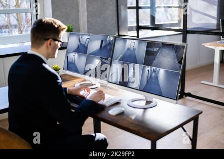 Operatore del sistema di sicurezza che guarda le riprese delle telecamere TVCC Foto Stock