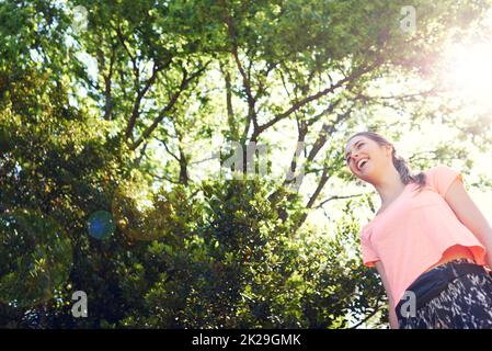 Allenarsi è il suo mood changer. Una giovane donna sportiva che cammina accanto agli alberi. Foto Stock