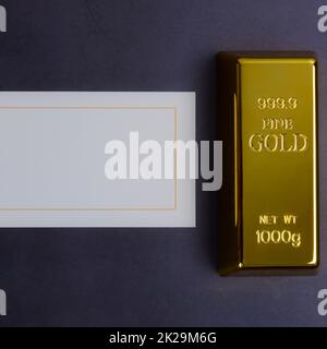 Un lingotto di oro metallo Bullion di puro brillante su uno sfondo grigio testurizzato. Foto Stock