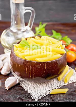 Penne in una ciotola di cocco con verdure su tavola marrone Foto Stock