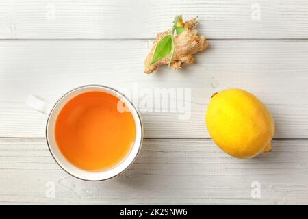 Vista del piano portapaziente, bianco bicchiere di fresco con infuso di tè allo zenzero, limone sul lato, radice secca con il germoglio verde di cui sopra. Foto Stock
