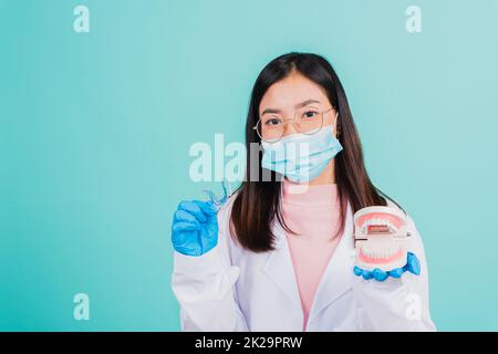 dentista donna che tiene fermi ortodontici in silicone e dentiera modello Foto Stock