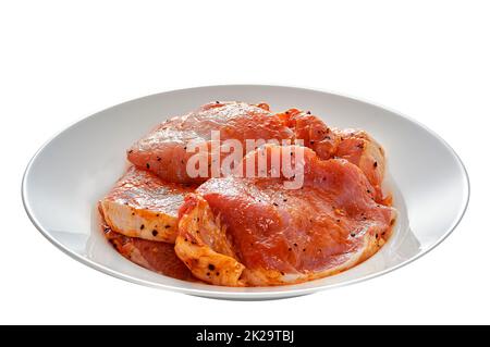 Il maiale in marinata si trova su un piatto bianco su uno sfondo bianco isolato Foto Stock