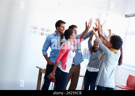 Theres non migliore lavoro che lavoro di squadra. Girato di un gruppo di uomini d'affari casualmente vestiti in ufficio. Foto Stock