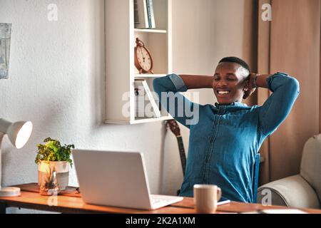 La gioia di essere lavoratori autonomi. Scatto corto di un bel giovane uomo d'affari seduto nel suo ufficio domestico con le sue mani dietro la sua testa nella realizzazione. Foto Stock