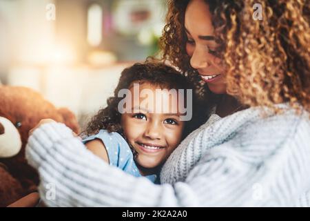 La mamma abbraccia, niente di simile a loro. Scatto di una bambina adorabile e sua madre in un caldo abbraccio a casa. Foto Stock