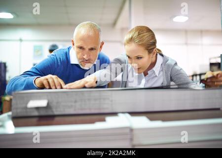 Garanzia di qualità durante l'intero processo di stampa. Due editori valutano la qualità del lavoro stampato in una fabbrica. Foto Stock