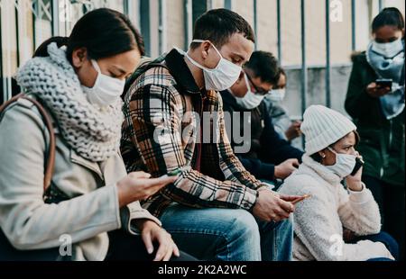 Social media, la nostra più grande connessione con i propri cari. Scatto di una giovane donna utilizzando uno smartphone e indossando una maschera durante il viaggio in una città straniera. Foto Stock