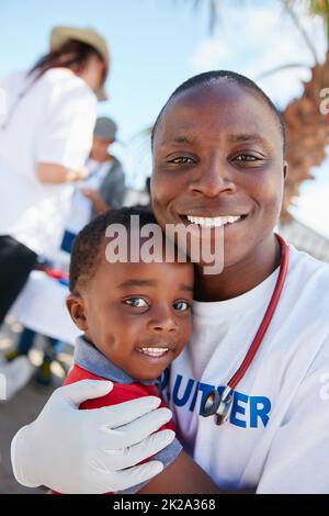 Volontariato per l'amore dei bambini. Ritratto di un medico volontario che si prende cura di dare controlli ai bambini svantaggiati. Foto Stock