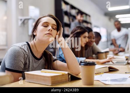 Im solo chiudendo gli occhi per un po'. Scatto di una giovane donna che guarda stanca mentre studia in una biblioteca del college nella biblioteca. Foto Stock