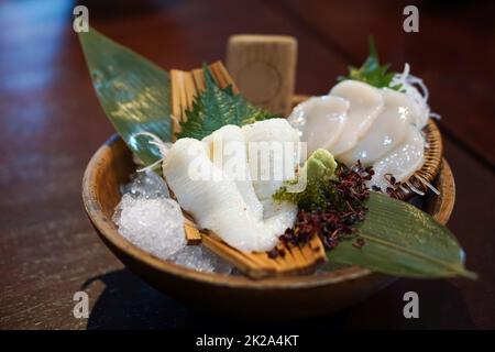 Il set sashimi è ben organizzato in un piatto di legno decorato con foglie di bambù verde. Buffet di cucina Giapponese. Scelta dello chef: Engawa, caldo Foto Stock