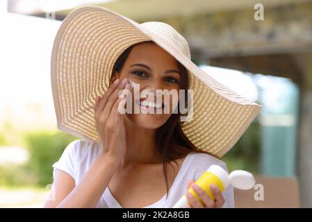 Meglio sicuro che spiacente. Una giovane donna attraente che applica la protezione solare al suo viso. Foto Stock