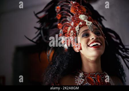 L'esecuzione dal vivo porta un sorriso a tutti. Scatto corto di una bella ballerina samba che indossa un headdress. Foto Stock