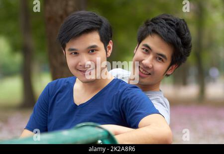 Godere della libertà di essere se stessi. Simpatica giovane coppia gay asiatica sorridente insieme mentre si siede nel parco. Foto Stock