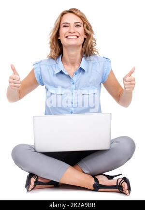 Darti il thumbsup. Ritratto a tutta lunghezza di una giovane donna attraente che dà due pollici in su mentre usando il suo laptop. Foto Stock