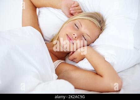 Fuori a slumberland.... Giovane donna sdraiata sul letto con le braccia distese e gli occhi chiusi. Foto Stock