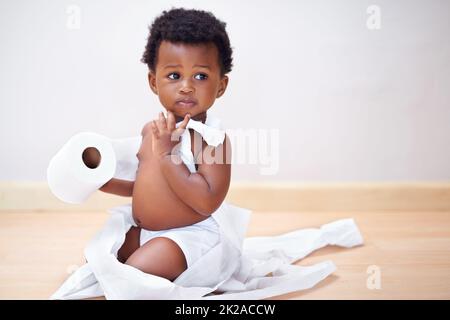 Giuro che il cane l'ha fatto. Scatto di un bambino carino intrappolato in un rotolo di carta igienica. Foto Stock