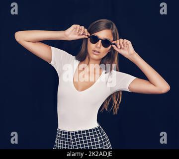 Per una freschezza senza tempo. Studio girato di una giovane donna attraente che tiene i suoi occhiali da sole. Foto Stock