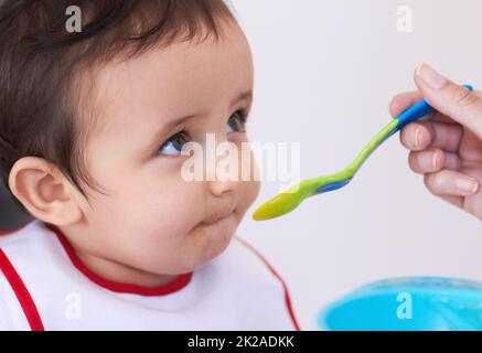 Ha un appetito sano. Un bambino carino che viene nutrito dalla mano delle sue madri. Foto Stock