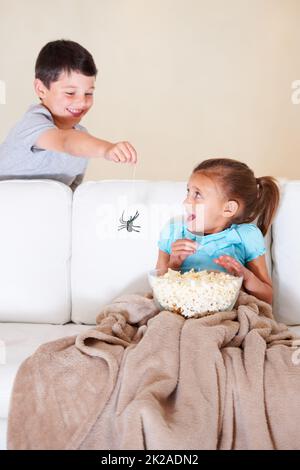 Gotcha. Il giovane ragazzo malizioso che spaventa la sua sorellina ad Halloween con un ragno di gomma. Foto Stock