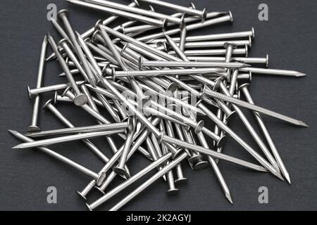 Mucchio di chiodi metallici argentati su sfondo nero Foto Stock