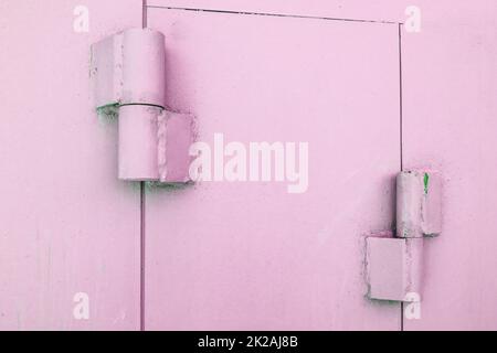Primo piano delle cerniere metalliche sui cancelli di un garage in metallo, verniciato di rosa, all'aperto Foto Stock