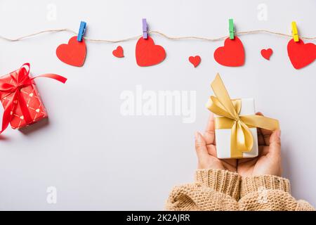 Mani di donna che tengono il regalo o la scatola del presente decorata e sorpresa rossa del cuore Foto Stock