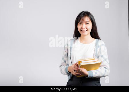 Donna giovane sorridente tenendo e abbracciare abbracciare il libro preferito per l'amante Foto Stock